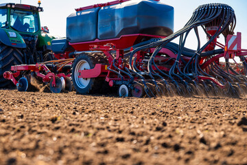 A green tractor tows a red air seeder with hoses and openers, cutting parallel furrows as dust rises from prepared soil. Side light defines seed tanks and lines. © True Pixel Art