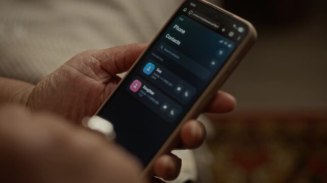 Closeup of senior citizen holding smartphone, navigating contacts list to call family members. Footage is perfect for marketing campaigns focusing on elderly care, technology, and family communication