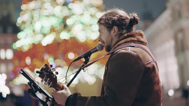 Street Musician Performs Guitar and Sings Amidst Christmas Lights in Warsaw