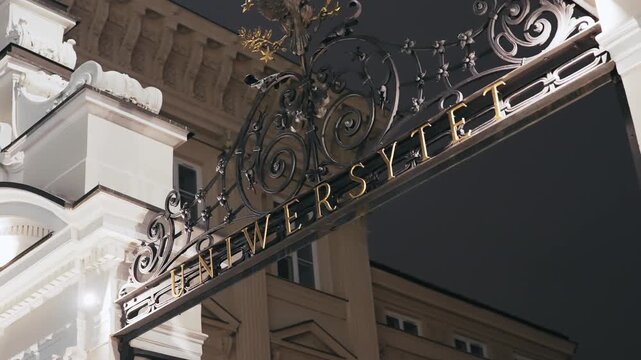 Warsaw University Gate Entrance Sign with Eagle Crest at Night