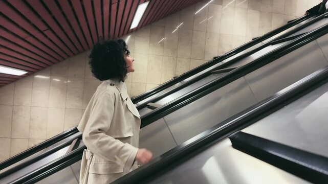 Business Woman Ascends Metro Escalator in Stylish Trench Coat
