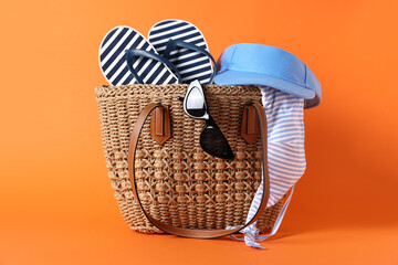 Fototapeta premium Bag with beach accessories on orange background