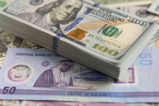 US dollar banknotes stack on United Arab Emirates dirham bills close up