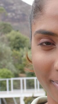 Vertical video: Reacting to camera cue, woman in light top opening eye and smiling near white rail