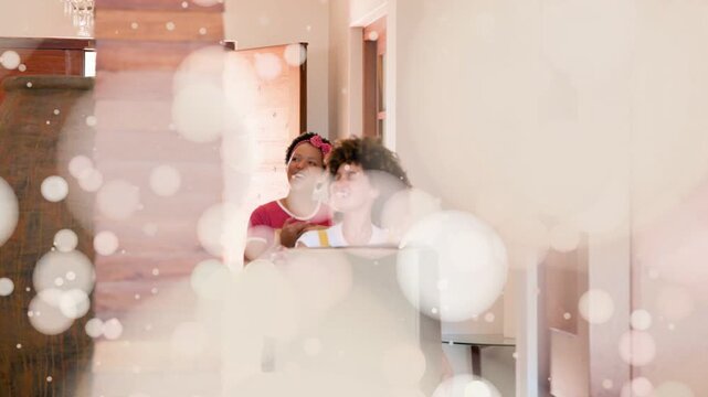 Two women carrying boxes entering hallway, bokeh overlay thinning revealing home for unpacking