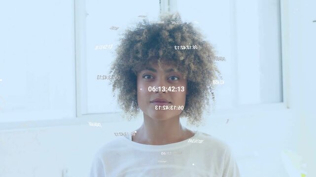 Woman standing before bright window, camera rolling, data overlays forming around face for tech