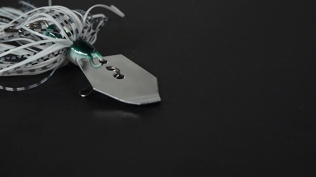 Bladed jig fishing lure moving across black surface