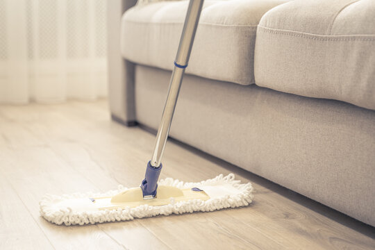 Modern white mop being used for cleaning a wooden floor