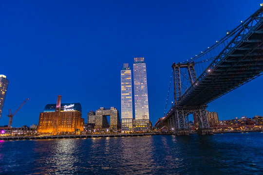 New York City, USA &ndash; April 12, 2026: The Manhattan Bridge and Brooklyn waterfront skyline illuminate the East River during blue hour in New York City.