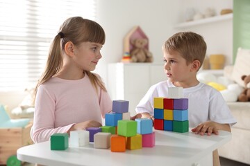 Fototapeta premium Little kids playing with colorful blocks at white table indoors