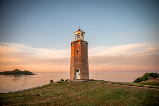 Groton, Connecticut, USA - Avery Point Lighthouse With Tanker On Long Island Sound At Sunrise