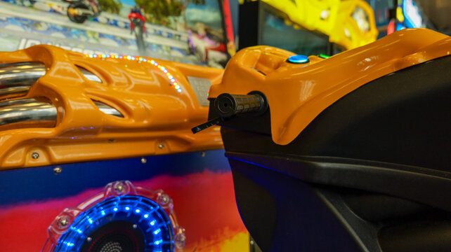Close-up of bright orange motorcycle arcade game controls and lights
