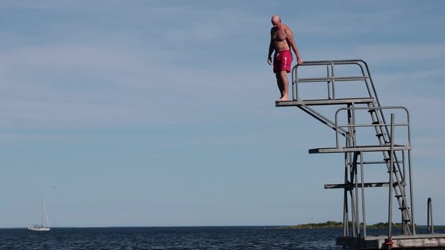 Karlskrona, Sweden A man jumps from a diving board into the Baltic Sea during summer.  