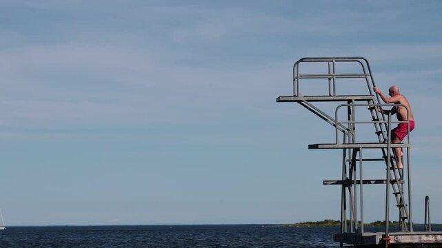 Karlskrona, Sweden A man jumps from a diving board into the Baltic Sea during summer.  
