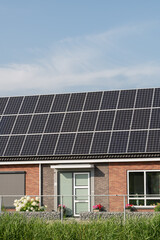 Fototapeta premium Breskens, Netherlands. Residential house with solar panels and garden illustrating sustainable living and decentralized energy production