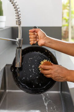 Washing cast iron skillet with eco friendly cleaning products in kitchen