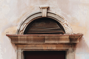 Weathered arched ventilation grille on an old historic building facade © Elninho