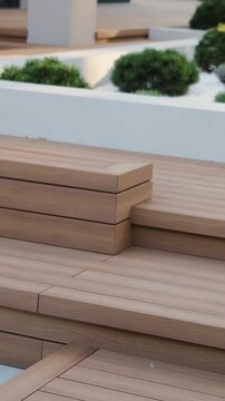 Vertical video. Modern outdoor terrace with wooden stairs, landscaped garden and house exterior.