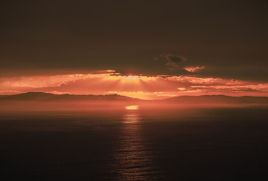 Aerial view of Sharp Point Lookout at sunset with dramatic clouds and golden light rays reflecting on the ocean surface in Torndirrup, Western Australia, Australia.