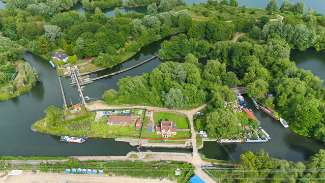 Aerial view of Feildes Weir Lock No.5 on the River Lee, featuring narrowboats, lush greenery, and historic lock structures in Hoddesdon, England, United Kingdom.