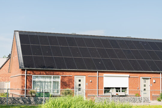 Breskens, Netherlands. Residential house with full rooftop solar panel installation showing real-world wear and suburban setting