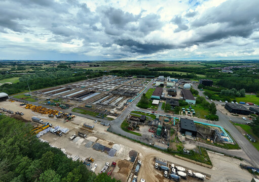 Aerial view of Alpheus Wastewater Sewage Treatment works featuring large rectangular treatment tanks, industrial buildings, and storage areas in Milton Keynes, England, United Kingdom.