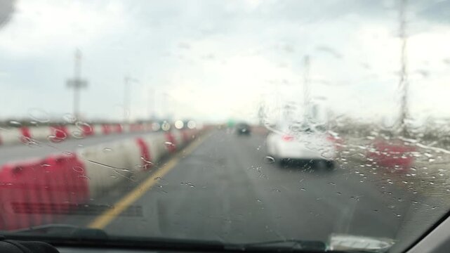 Glass rain auto. A car ride in a heavy downpour. Blurry traffic on the road, headlights of oncoming cars out of focus. The concept of bad weather, storm, hurricane. A gray, rainy, dreary autumn day.