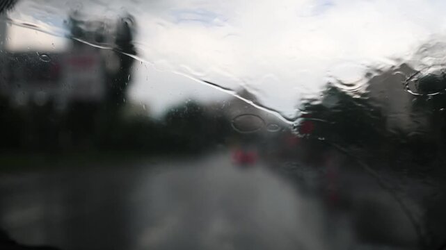 Glass rain auto. A car ride in a heavy downpour. Blurry traffic on the road, headlights of oncoming cars out of focus. The concept of bad weather, storm, hurricane. A gray, rainy, dreary autumn day.