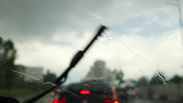 Glass rain auto. A car ride in a heavy downpour. Blurry traffic on the road, headlights of oncoming cars out of focus. The concept of bad weather, storm, hurricane. A gray, rainy, dreary autumn day.
