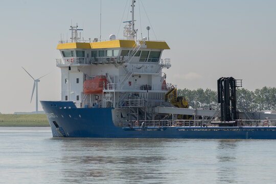 21 June 2026, Breskens, Netherlands. Trailing suction hopper dredger on the Westerschelde with offshore wind turbine illustrating coastal engineering and energy transition