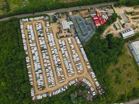 Aerial view of Weldon Caravan Storage showing rows of parked caravans and motorhomes on gravel paths surrounded by lush green trees in Weldon, England, United Kingdom.