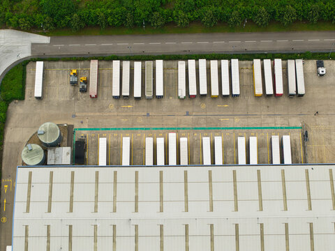 Aerial view of Corby Gate Business Park showing rows of parked semi-trailers at a logistics facility with a large warehouse building in Corby, England, United Kingdom.