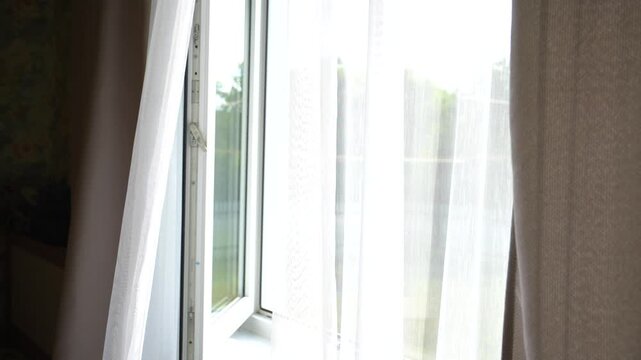 an open window with white curtains fluttering in the wind
