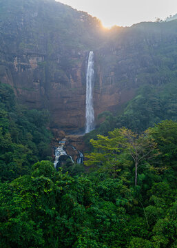 Aerial view of Cikanteh Waterfall cascading down a rocky cliff face surrounded by lush tropical rainforest in Geopark Ciletuh, West Java, Indonesia.