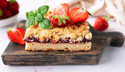 Sweet homemade pie with strawberry jam, decorated with fresh strawberries and aromatic herbs on the wooden tray on white marble table close up. © Iryna