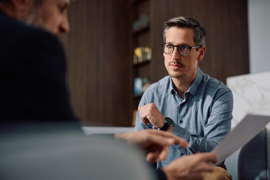 Mid adult man having meeting with financial counselor in office.