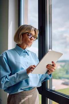 Female CEO reading email on digital tablet in office.