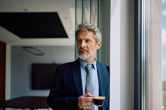 Mature CEO having cup of coffee in office.