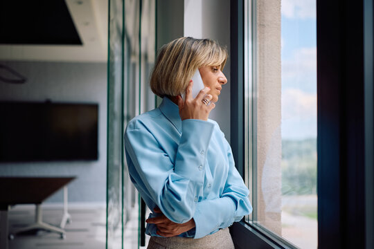Pensive businesswoman talking on cell phone while working in office.
