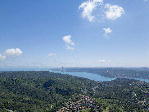 Aerial view of the Yavuz Sultan Selim Bridge spanning the Bosphorus, surrounded by lush green forests and a small village in Istanbul, Istanbul, Turkiye.