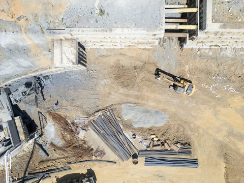 Aerial view of construction site with heavy machinery, excavators, and steel reinforcement bars on a dusty ground in Istanbul, Istanbul, Turkiye.