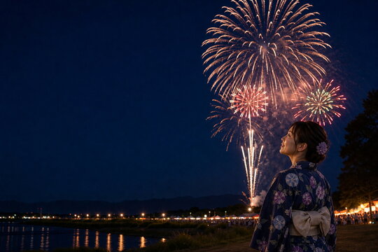 川辺の花火大会を見上げる浴衣の女性