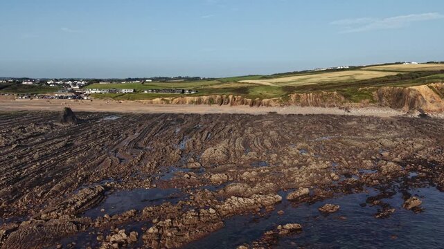 Large rock and sandy beach at Widemouth Bay in Cornwall on a sunny summer afternoon