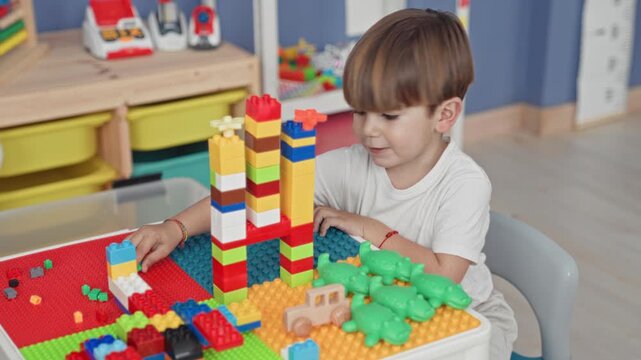 Boy stacking colorful plastic blocks into a tall tower on a toy baseplate with a small wooden car and green crocodile toys in a studio play area; quiet concentration.