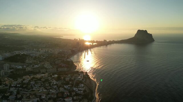 Breathtaking aerial view of a coastal city at sunrise, with golden light reflecting beautifully on the calm ocean waters and illuminating the distant skyline. Serene and picturesque landscape.