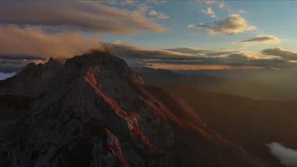 Amazing rocky mountains in clouds at sunset © Kokhanchikov