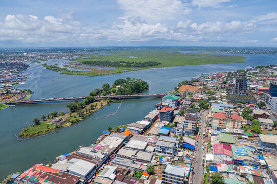 Aerial view of the Mesurado River and bridge connecting urban districts, surrounded by buildings and lush vegetation in Monrovia, Montserrado, Liberia.