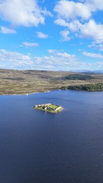 Lochindorb Castle in Scotland , scottish highland is barely visible from extreme distance, a 13th-century ruin surrounded by vast loch and Highland wilderness.