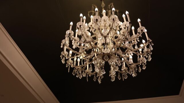 Elegant crystal chandelier on dark ceiling