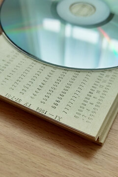Concept of data storage evolution, retro punch cards and optical disc on wooden table